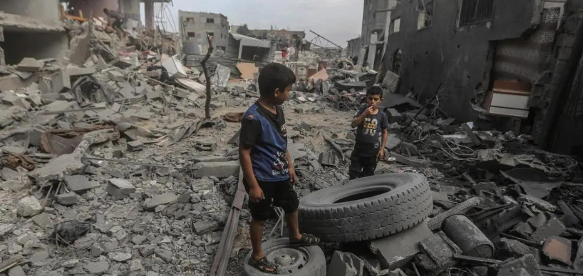 Palestinian children stand amid the rubble of destroyed buildings