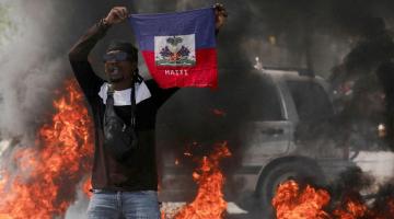 Man holding Haitian flag in front of fire