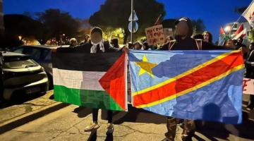 Two demonstrators standing side by side with one holding Palestine flag and other holding DR Congo flag