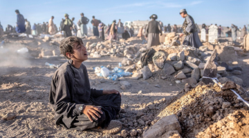 An Afghan boy mourns next to a grave of his little brother who died due to an earthquake.