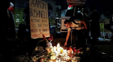 A mourner places incense at a memorial for Aaron Bushnell
