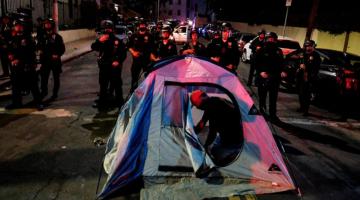 A man sets up a tent in front of police