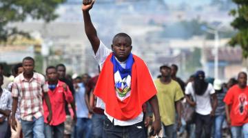 Haitian person holding their fist in the air at a protest